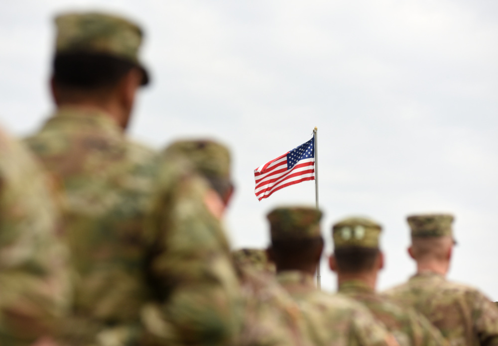 A group of soldiers standing in front of an american flag.